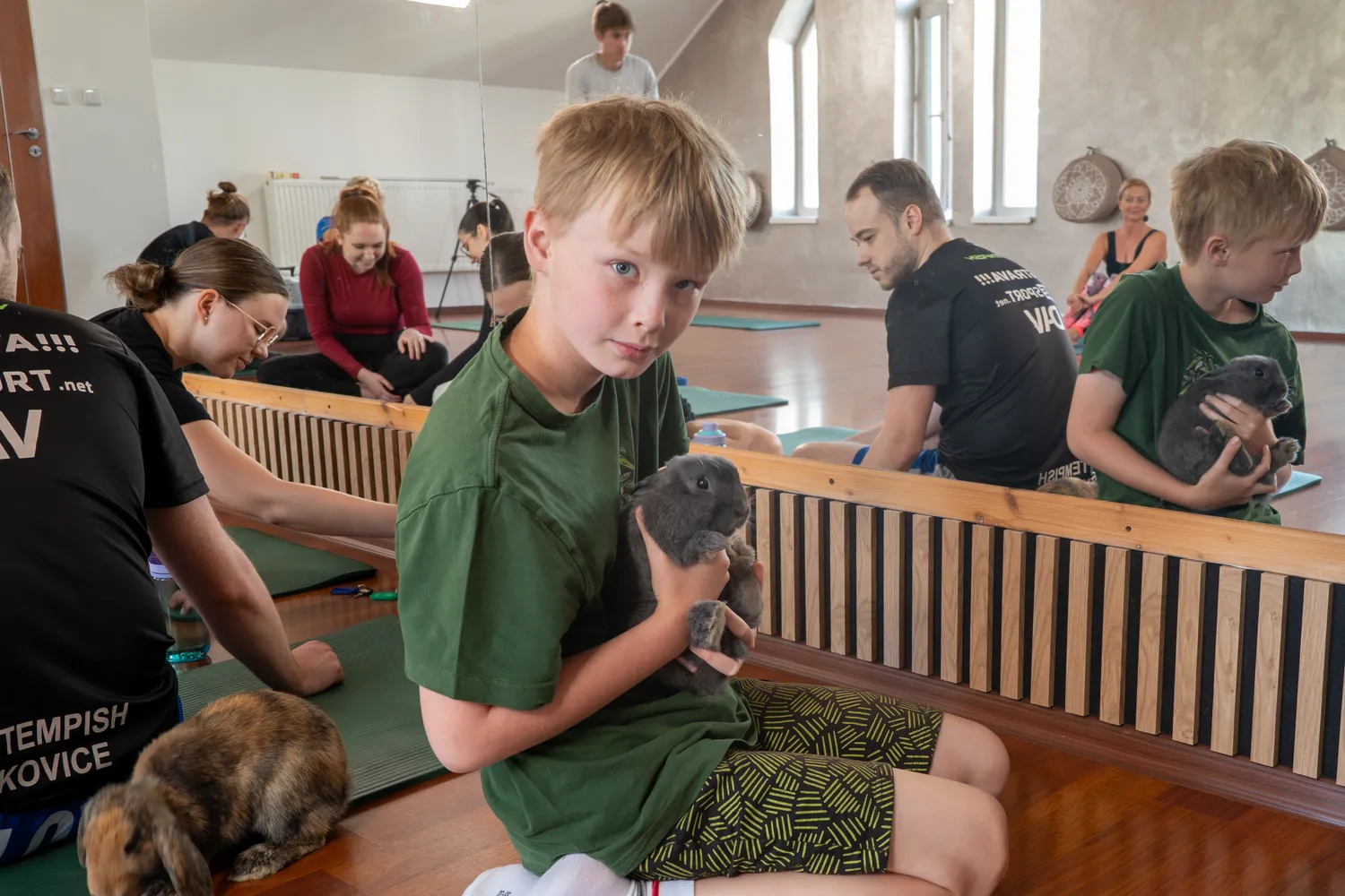 Chlapec na dětské lekci drží v náručí šedého králíka